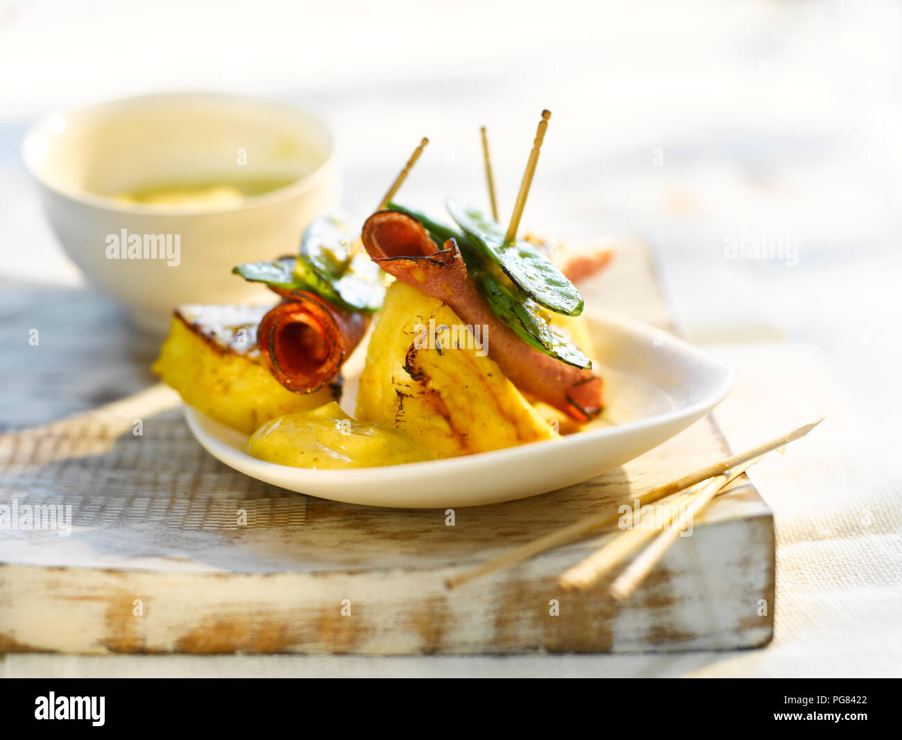 Gegrillte Ananas mit Schinken, Zuckererbsen und Currysauce Stockfoto
