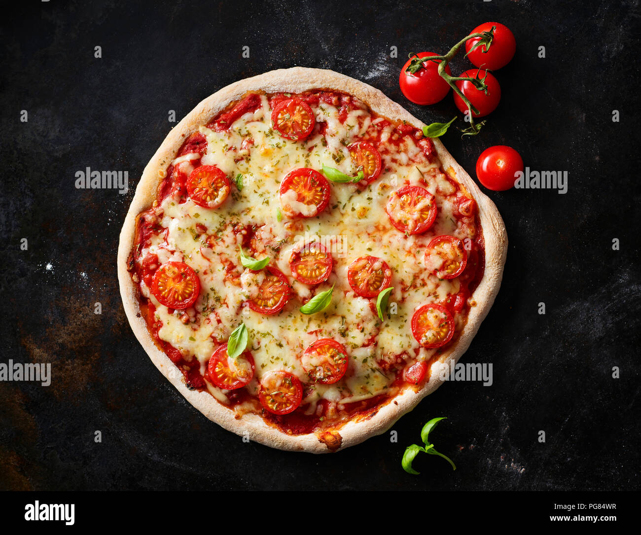 Pizza Margherita und Kirschtomaten auf dunklem Boden Stockfoto
