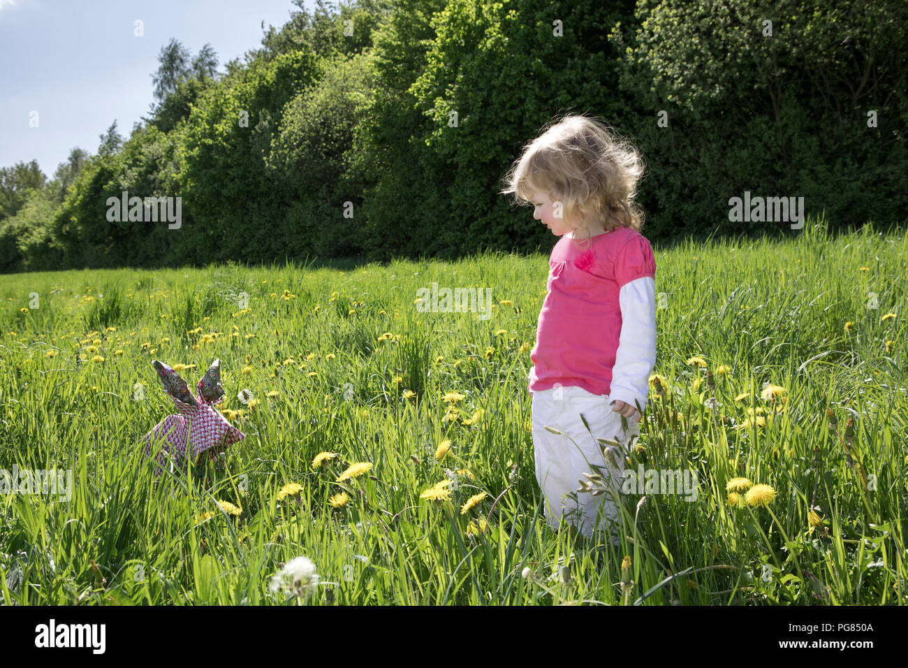 Kleines Mädchen mit Origami Hase auf der Wiese Stockfoto
