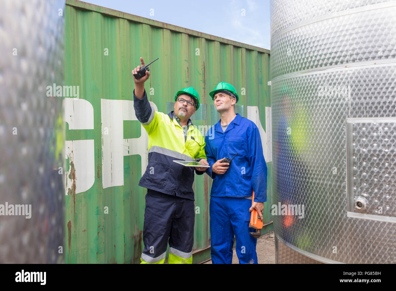 Arbeiter mit Tablet am Container im Gespräch mit Mitarbeiter Stockfoto