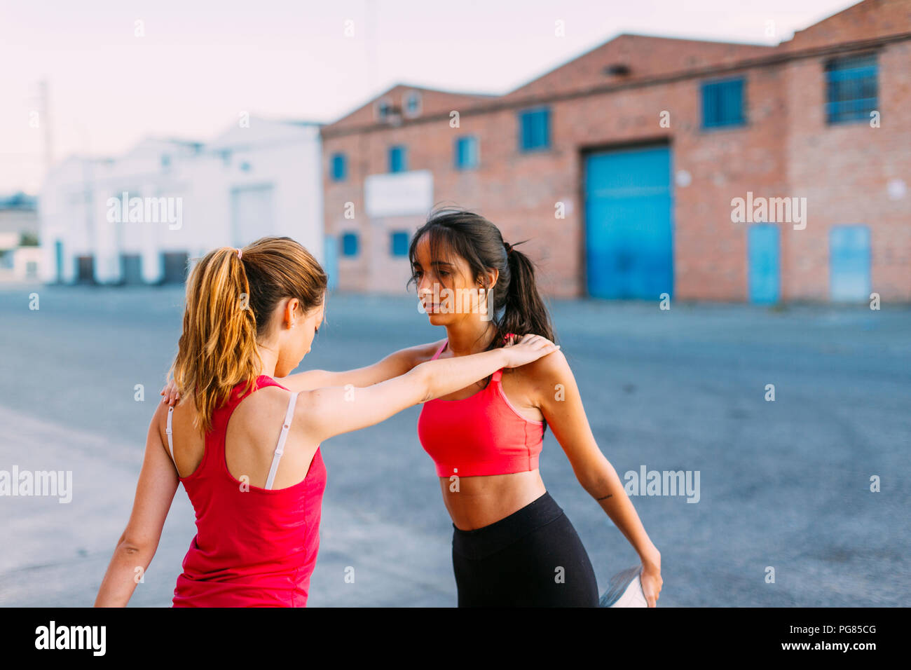 Zwei aktive Frauen dehnen und einander unterstützen Stockfoto