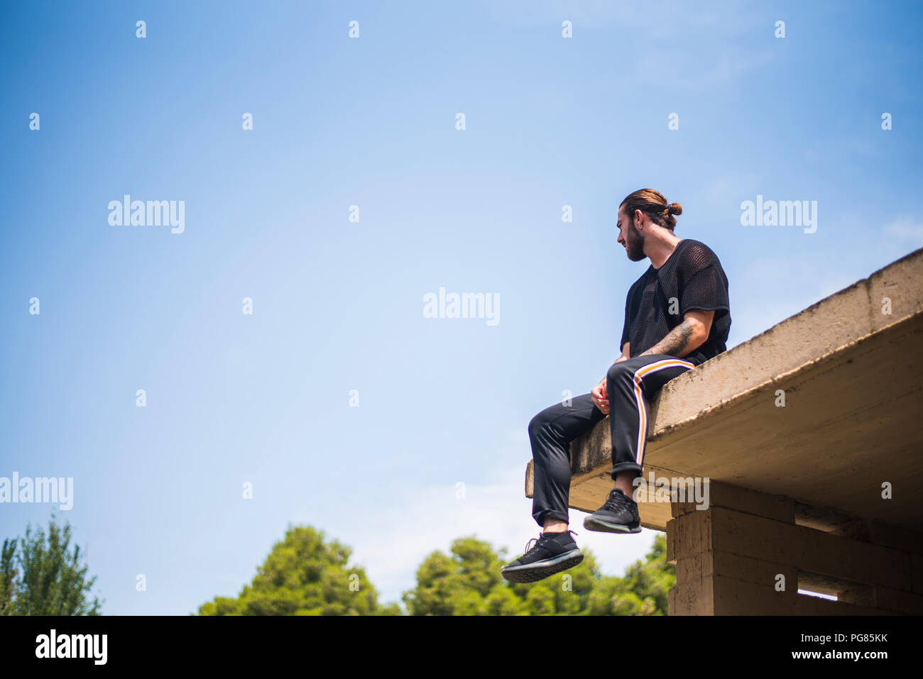 Tätowierten Mann sittin auf dem Dach Stockfoto