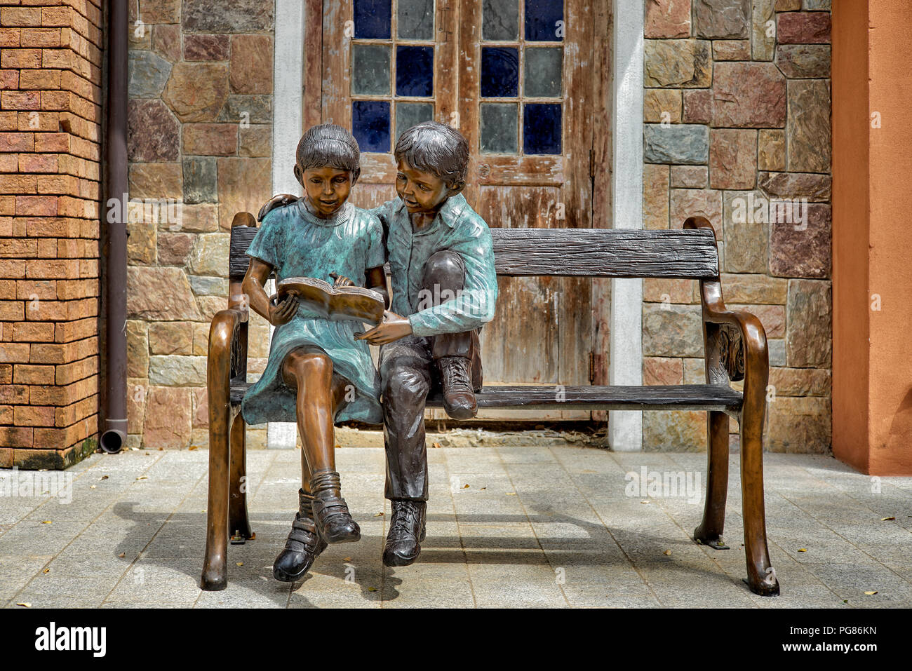 Statue Junge und Mädchen sitzen auf einer Bank, Buch lesen, zusammen. Zweisamkeit Stockfoto