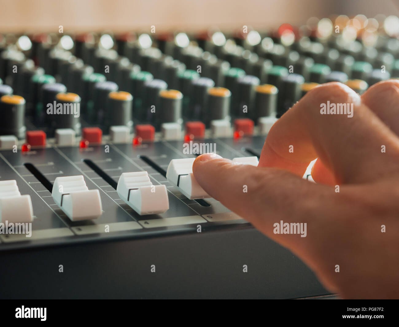 Mann Einstellung Fade Schieberegler auf Audio Mixer im Studio im Innenbereich Stockfoto