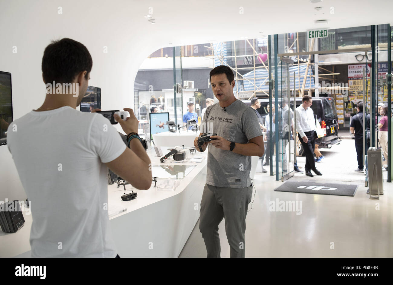 Hong Kong, Hong Kong Island. 24 Aug, 2018. Kunden, ein Video mit dem neuen DJI Mavic 2 Drohne und sein Controller an die chinesische multinationale Technologieunternehmen DJI Flagship Store in Hongkong.Drone Manufacturing Leader DJI Veröffentlichungen 2 der neuesten Produkte, die marvic 2 Pro und die marvic 2 zoom am 23. August 2018. Die marvic 2 Pro ist mit einem Upgrade 1 Zoll Kamera Sensor für verbesserte Qualität ausgestattet, während das marvic 2 Zoom ermöglicht Benutzern die digitale Zoomfunktion im Flug zu benutzen. Credit: Miguel Candela/SOPA Images/ZUMA Draht/Alamy leben Nachrichten Stockfoto