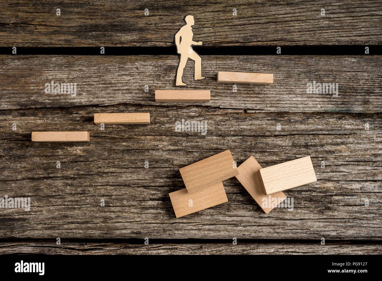 Silhouette Ausschnitte eines Mannes zu Fuß bis Holz- schritte mit Dominos über alten rauhen Holztisch Oberfläche. Stockfoto