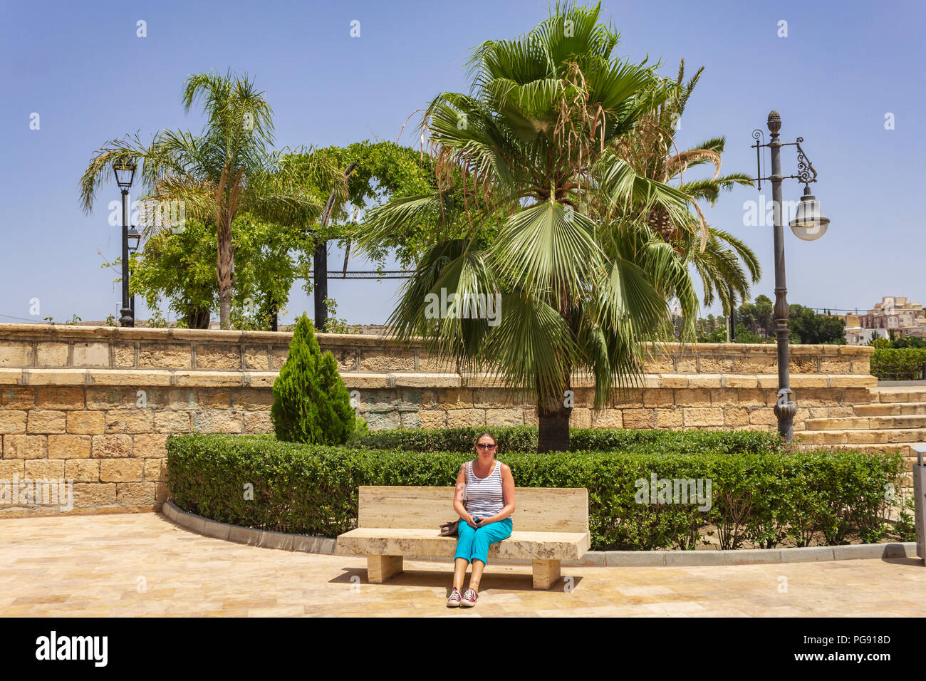 Kaukasische Dame im Urlaub auf einer Parkbank in Spanien Stockfoto