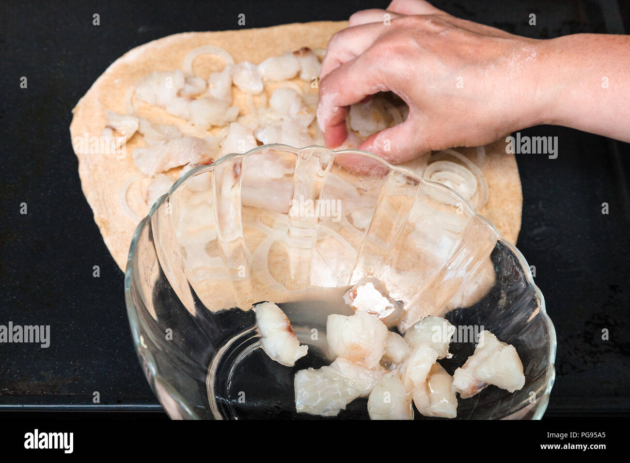 Zubereitung der Torte - Verbreitung von rohem Fisch Stücke auf Blatt von Teig Stockfoto