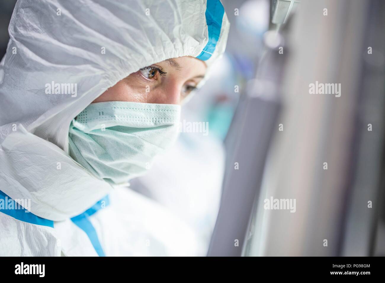 Nahaufnahme einer Laborantin tragen ein Schutzanzug und Gesichtsmaske im Labor, die in einem sterilen Umgebung erhalten. Stockfoto