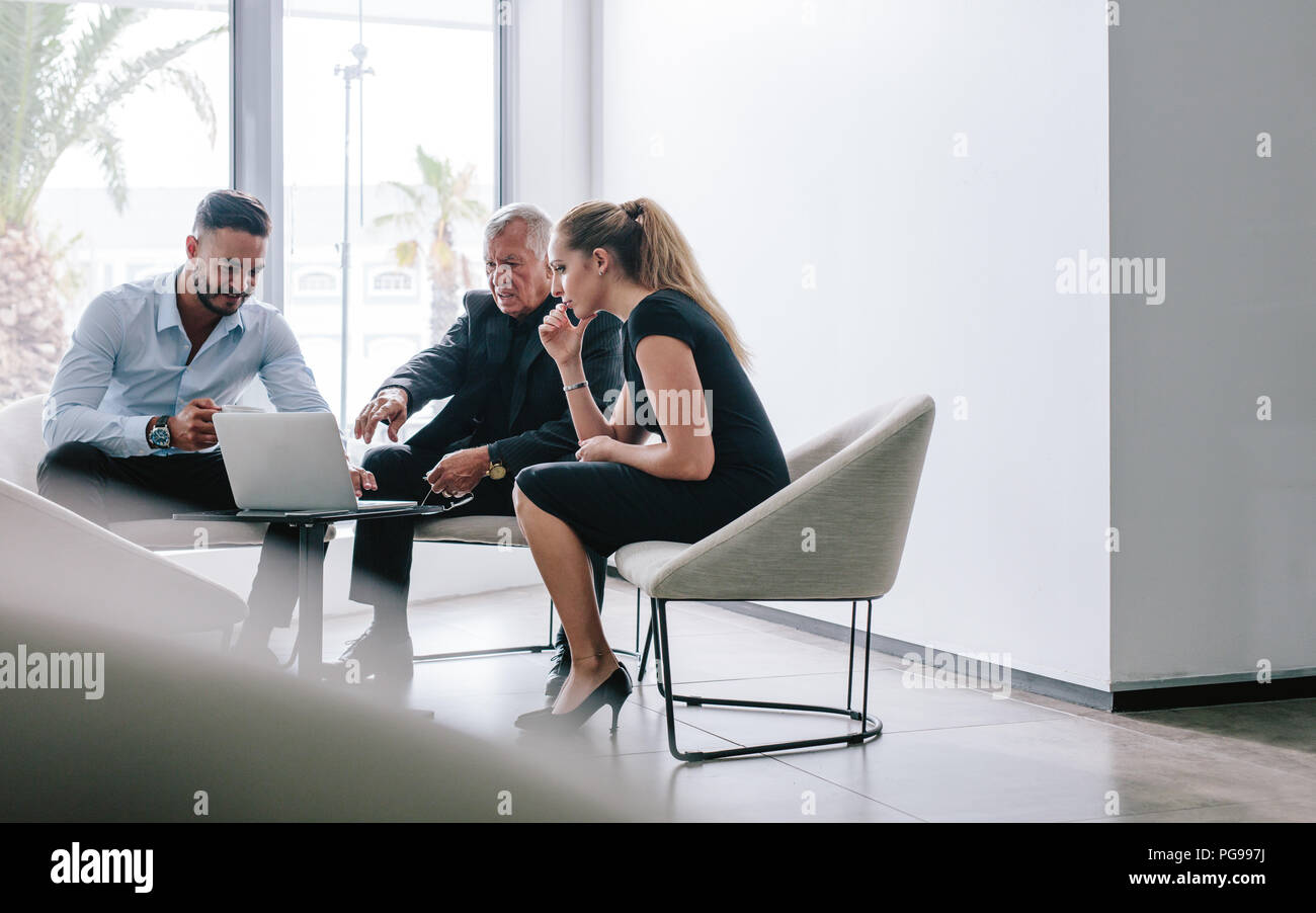 Drei Geschäftsleute in Office Lobby sitzen und diskutieren neue Projekt auf dem Laptop. Business Team zusammen auf Neues Projekt. Stockfoto