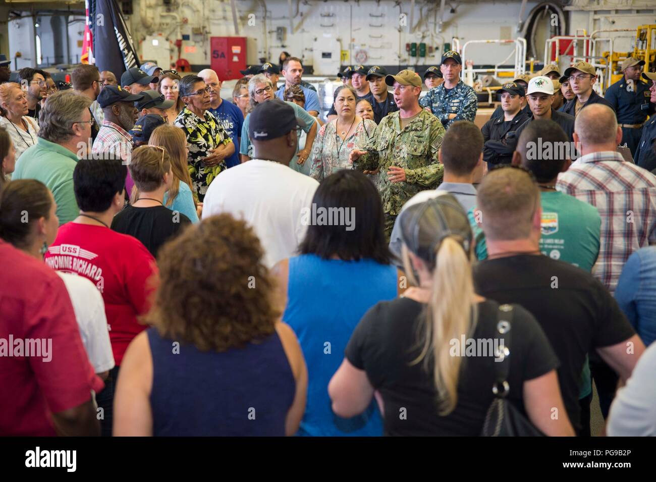 180818-N-XK 809-1022 SAN DIEGO (Aug. 18, 2018) Lt.Cmdr. Daniel Hodges, Mitte, Assistent der Abteilung Offizier des Amphibious Assault ship USS BONHOMME RICHARD (LHD6), grüßt Bonhomme Richard plankowners und ihre Gäste während einer Schiffstour. Die plankowners besucht Bonhomme Richard sein 20 Jahr der Service seit seiner Inbetriebnahme am 15 August, 1998 zu feiern. Bonhomme Richard ist in seinen Heimathafen San Diego. (U.S. Marine Foto von Mass Communication Specialist 2. Klasse William Sykes) Stockfoto