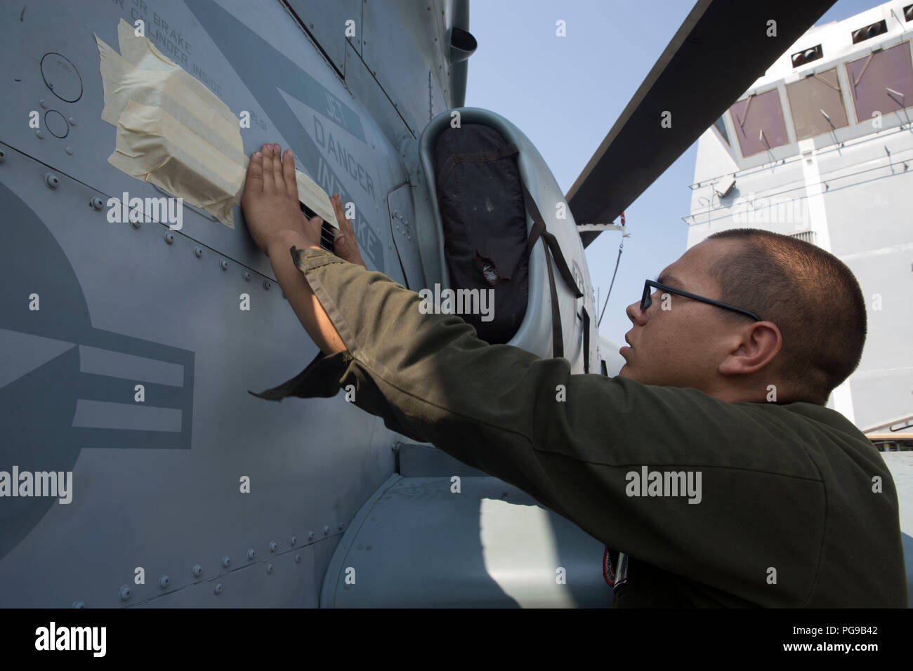 Pazifik - U.S. Marines Lance Cpl. Ryan Dabulskis eine Fluchtlinie Mechaniker mit Marine Medium Tiltrotor Squadron 166 verstärkt, 13 Marine Expeditionary Unit (MEU), deckt eine Falschluftansaugung vor dem Waschen der AH-1Z Viper an Bord der San Antonio-Klasse amphibious Transport dock USS Anchorage LPD (23), die während einer planmäßigen Einsatz der Essex Amphibious Ready Group (ARG) und 13 MEU, 18. August 2018. Das Essex ARG/13 MEU ist ein fähiger und tödliche Navy-Marine Corps Team der 7 Bereich der Flotte im Einsatz der regionalen Stabilität zu unterstützen, Partner und Verbündeten beruhigen und pflegen Stockfoto