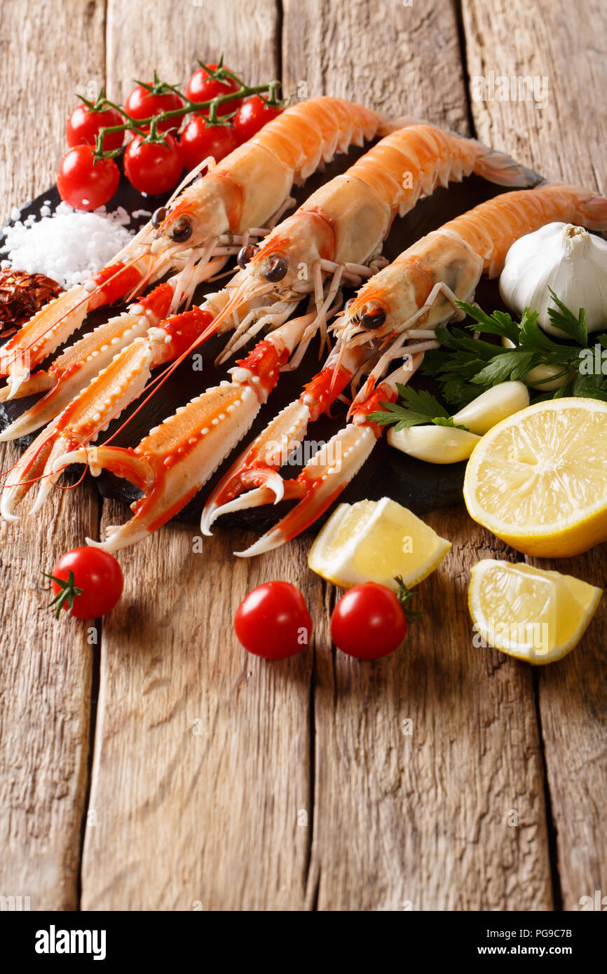 Frische rohe Scampi, Scampi mit Gemüse der Saison und Kräuter closeup auf einem Schild an einem Holztisch. Vertikale, rustikal Stockfoto