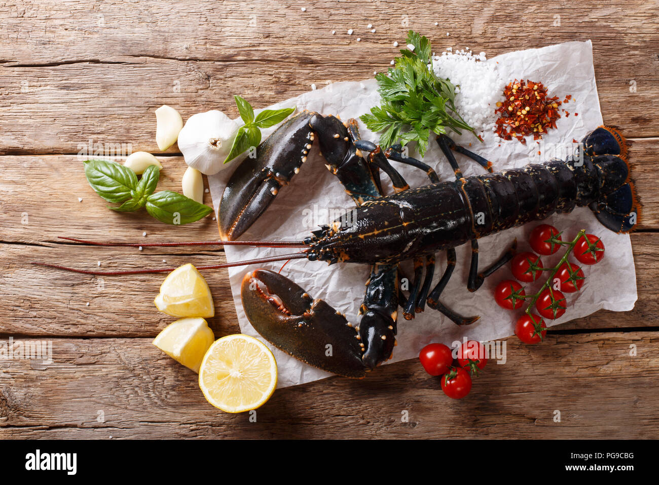 Schöne Meeresfrüchte nicht gegartem Hummer closeup mit Zitrone und Kräutern auf einem Holztisch. horizontal oben Ansicht von oben Stockfoto