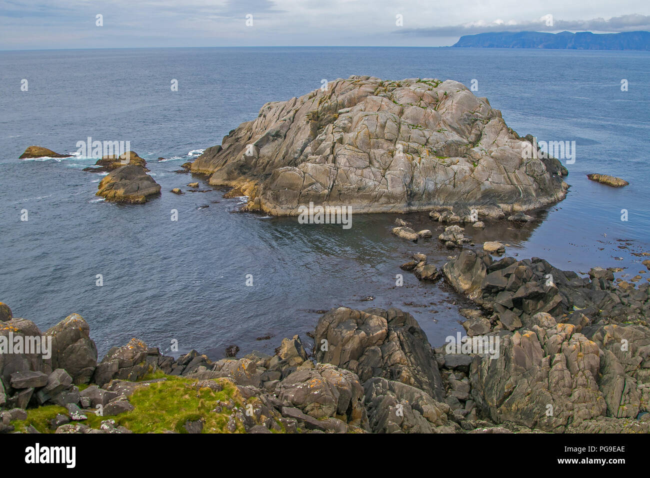 Küsten Norwegen. Ruhige Szene von natürlicher Schönheit. Felsige Küstenlinie, blau bewölkter Himmel, Berge am Horizont. Stockfoto