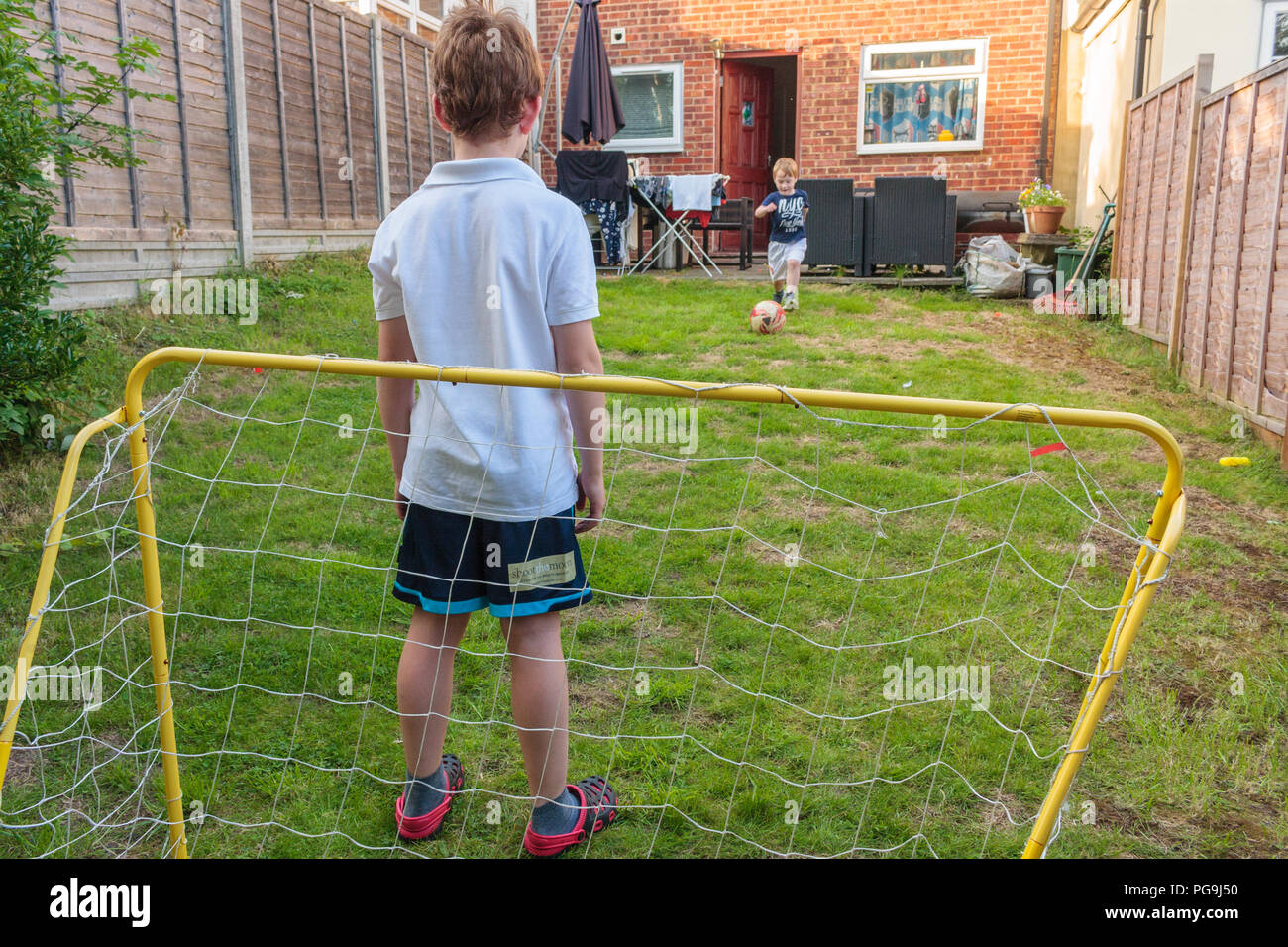 Zwei Jungs spielen Fußball in einem Garten auf der Rückseite Stockfoto