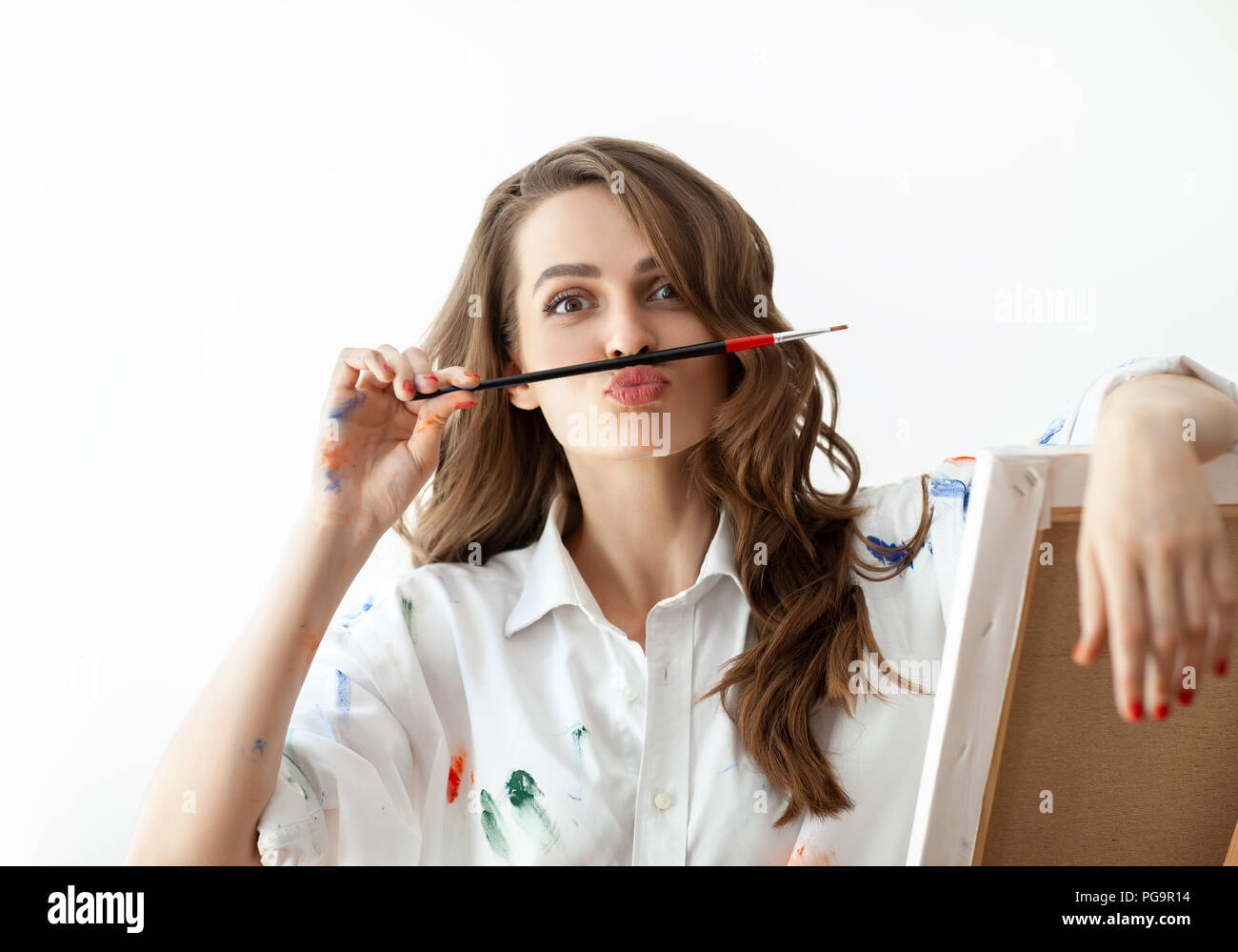 Porträt der jungen Frau, die Gesichter und schildert Schnurrbart mit Hilfe von Pinsel. Spaß-Konzept Stockfoto