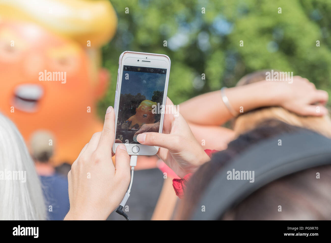 Eine Frau, die ein Foto mit Handy der Ballon von baby Donald Trump auf Protest in London. Stockfoto