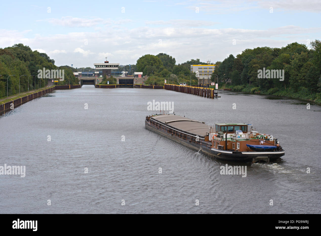 Ein lastkahn an einem Kanal in Richtung Schleuse. Stockfoto