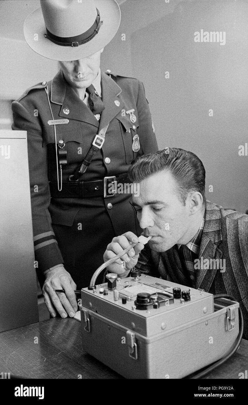 Ein Mann bläst in eine Alkohol Sensor Maschine. Ein breathalyzer oder Breathalyser (ein portmanteau von Atem und Analyzer Analyzer) ist eine Vorrichtung, die für die Schätzung der Blutalkoholkonzentration (BAK) von einer Atemprobe. Breathalyser ist der Markenname (a genericized trademark) für das Instrument, das die Tests der Alkoholgehalt von Erfinder Robert Frank Borkenstein. Es war wie eine Marke am 13. Mai 1954 registriert, aber viele Leute benutzen den Begriff auf alle Generic Device für die Schätzung der Blutalkoholgehalt zu verweisen. Stockfoto