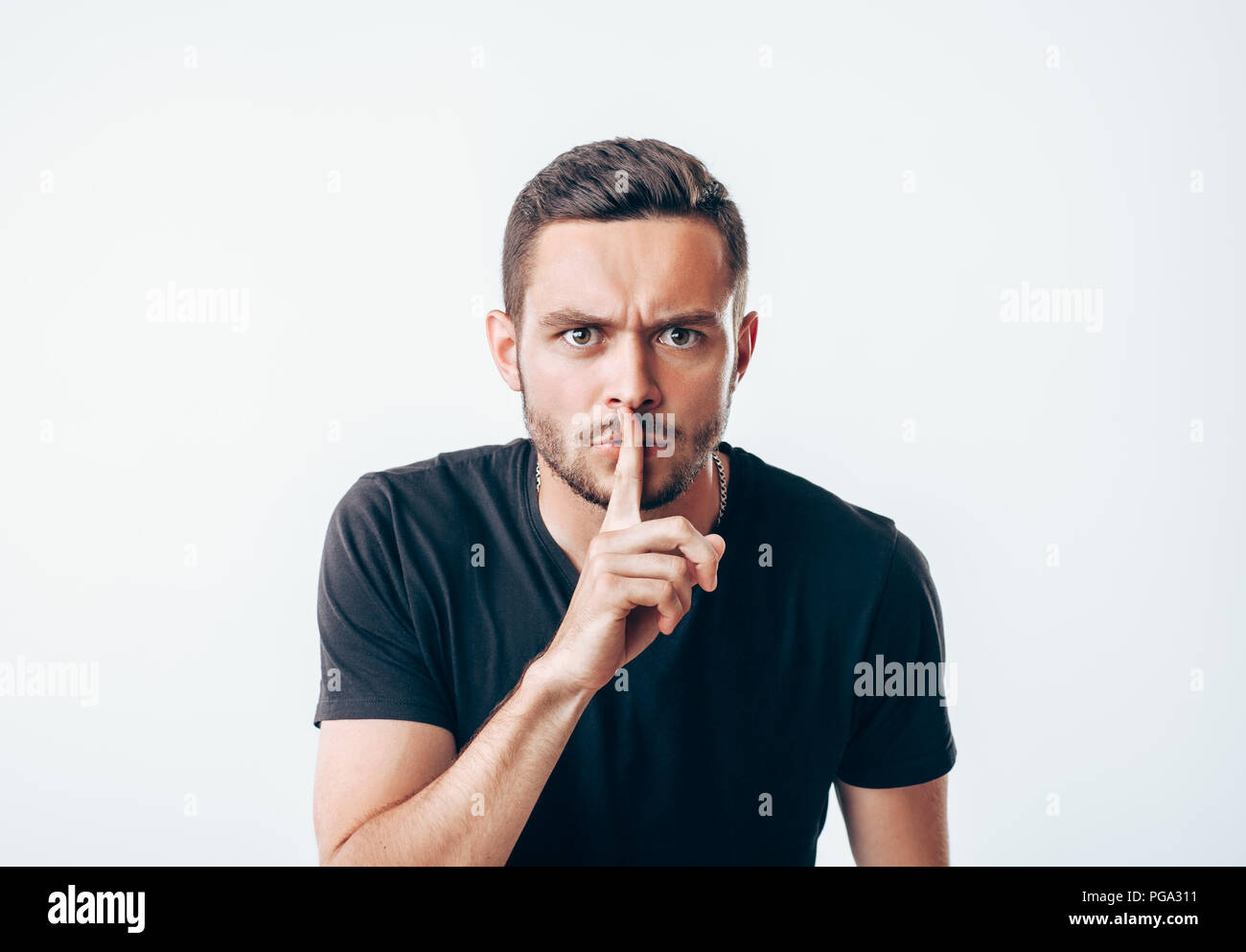 Junger Mann mit Zeigefinger auf die Lippen, die Stille. Geheime Konzept Stockfoto