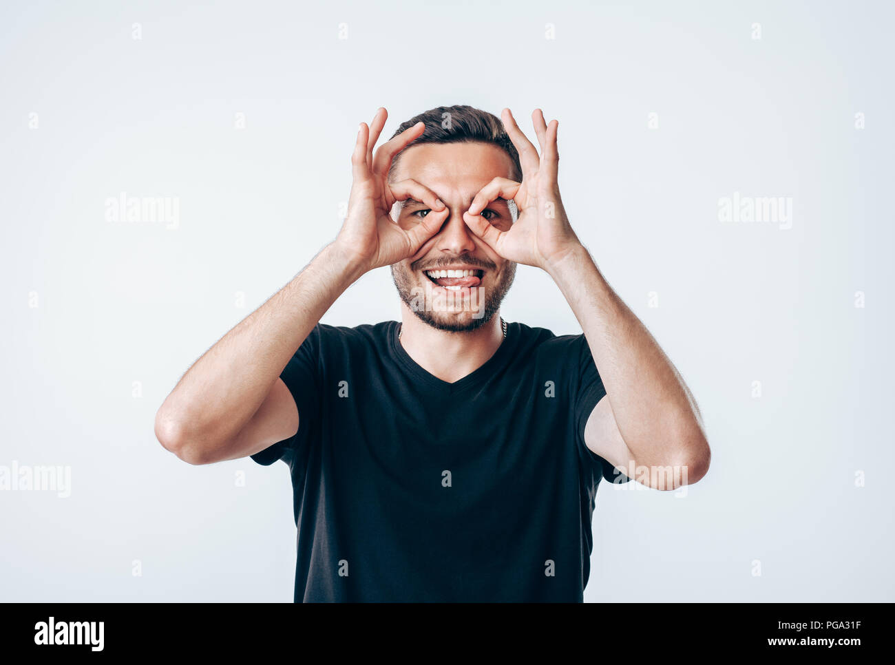 Die jungen Kreativen Menschen, die Finger in die Nähe von Augen wie eine Brille. Spaß-Konzept Stockfoto