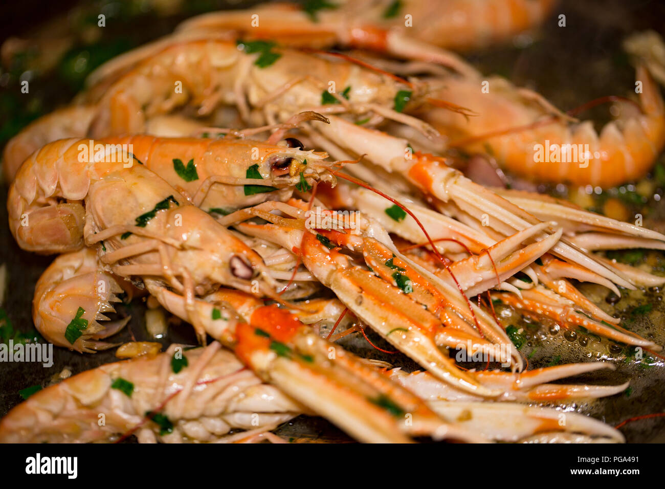 Schottischen Langustinen, Nephrops norvegicus, gekauft von einem Supermarkt und fotografierte Braten in einer Kupfer Pfanne mit Butter, Knoblauch und Petersilie. Das lan Stockfoto