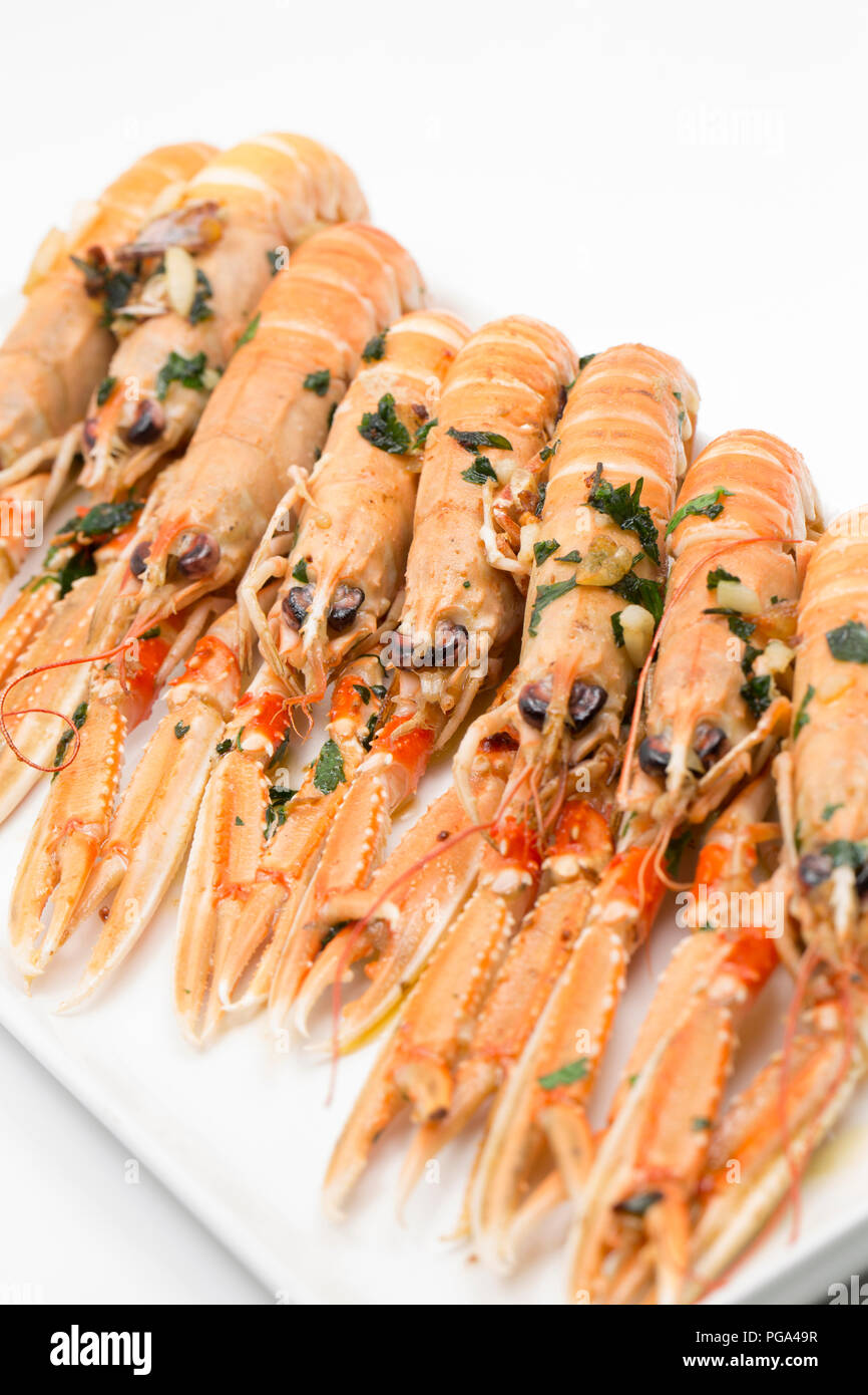 Schottischen Langustinen, Nephrops norvegicus, gekauft von einem Supermarkt und auf dem Teller fotografiert nach dem Braten in Butter, Knoblauch und Petersilie. Der lang Stockfoto