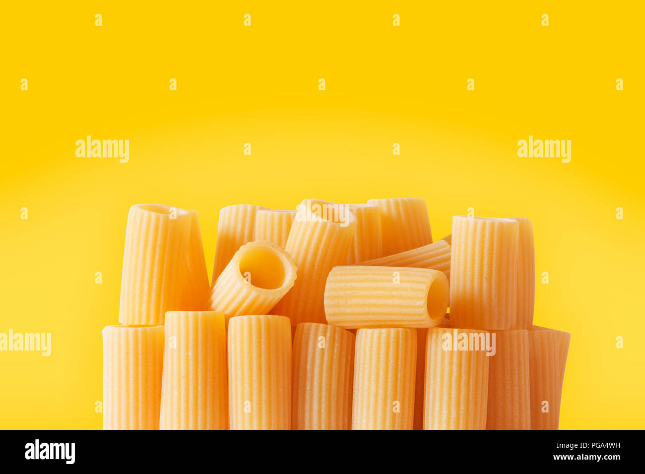 Italienische Pasta, Rigatoni auf einem farbigen Hintergrund, u-förmige Nudeln mit Bergrücken hinunter ihre Länge, studio Shot, Stockfoto