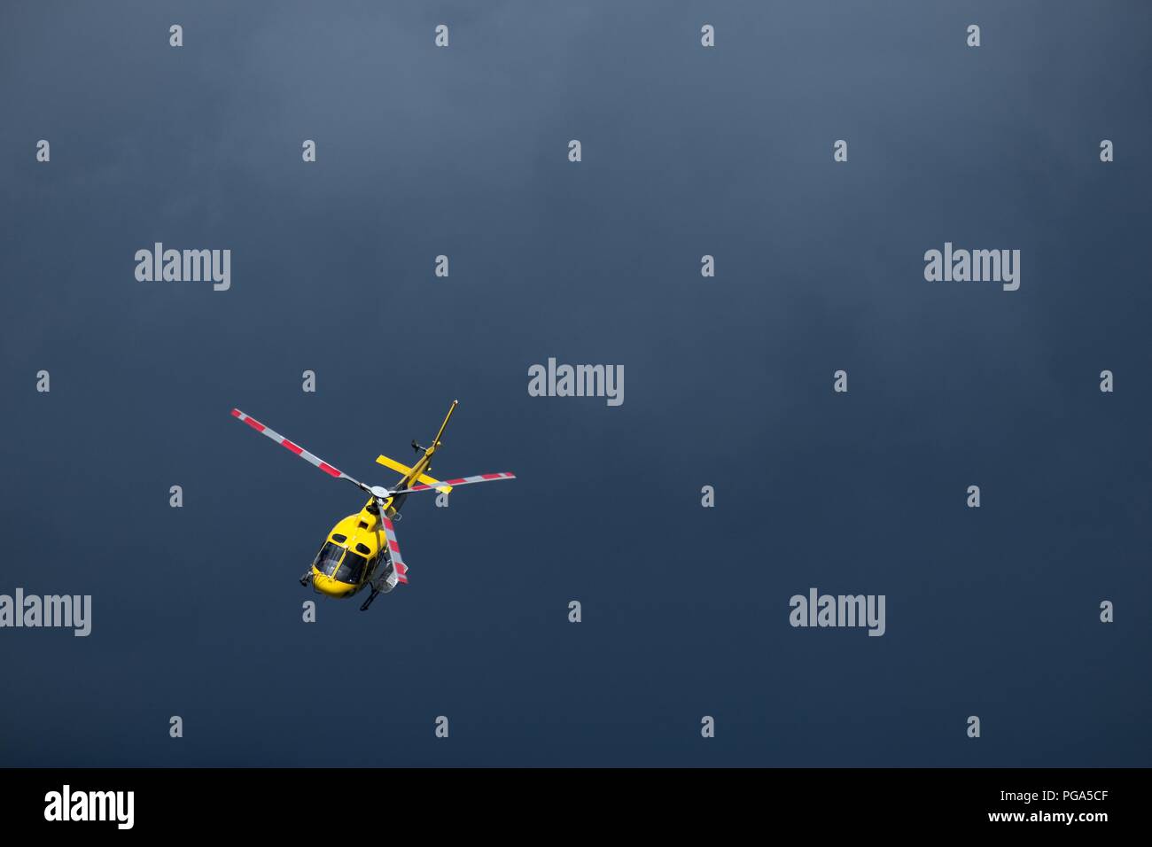 Gelbe Hubschrauber fliegen in den Himmel isoliert. Dramatischer Hintergrund mit Kopie Raum Stockfoto