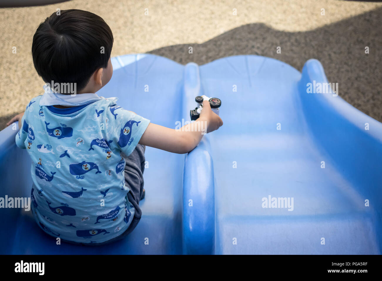 Ein Kind mit Spielzeug spielt auf einer Folie in der Spielplatz, Korea Stockfoto