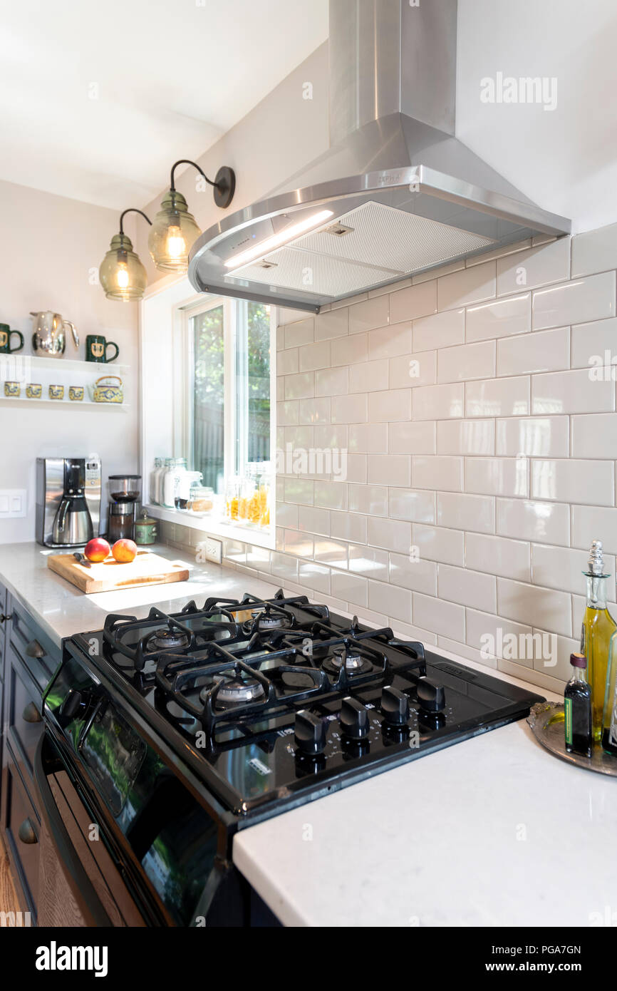 Ein Gas Herd in einer modernen Küche zu Hause mit einem elektrischen Belüftung Haube mit einem weißen Fliesenspiegel Stockfoto