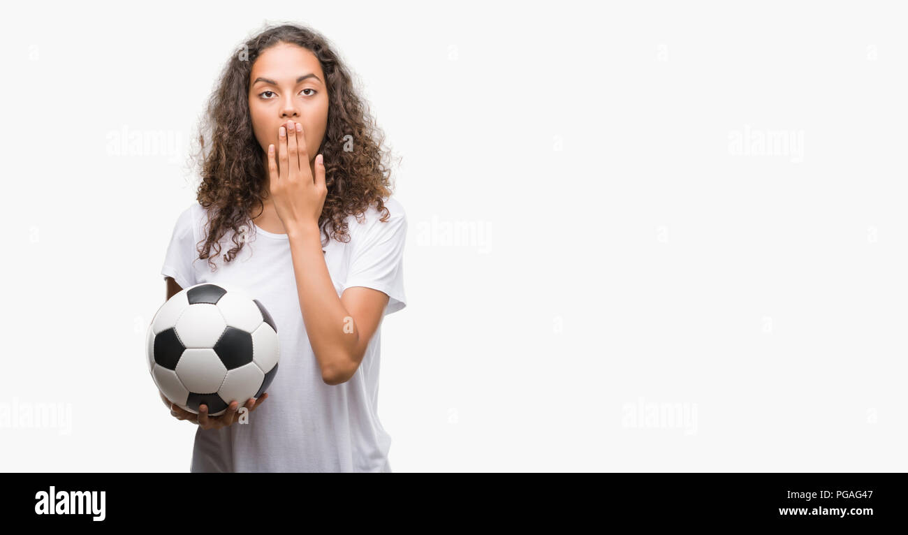 Junge Hispanic woman holding Fußball-Fußball-Abdeckung der Kugel den Mund mit der Hand mit Schande für den Fehler, den Ausdruck von Angst erschüttert, die in der Stille Angst, geheime Stockfoto