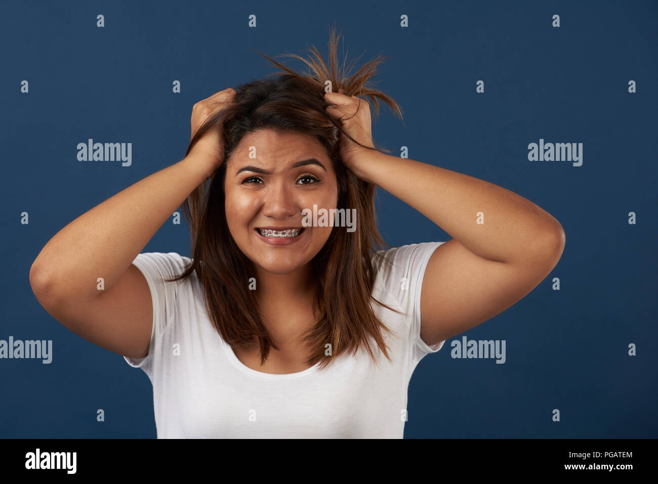 Wütende Frau emotion Thema. Latina Mädchen mit den Händen auf unordentlichen Haar Stockfoto