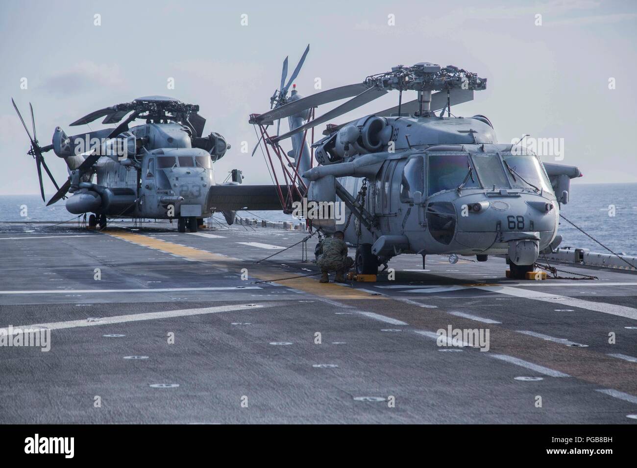 Pazifik - US Marine Staff Sgt. Daylan Aplaca, Wartungsdaten Chief mit Marine Fighter Attack Squadron 211, 13 Marine Expeditionary Unit (MEU), prüft die Kettenschlösser zu einem MH-60S Sea Hawk zum "Blackjacks" der Hubschrauber Meer Combat Squadron 21 angebracht, an Bord der Wasp-Klasse amphibisches Schiff USS Essex (LL 2), während einer planmäßigen Einsatz der Essex Amphibious Ready Group (ARG) und 13 MEU, 13. August 2018. Das Essex ARG/13 MEU Team ist ein fähiger und tödliche Navy-Marine Corps Team der 7 Bereich der Flotte im Einsatz sind regionale Stabi zu unterstützen. Stockfoto