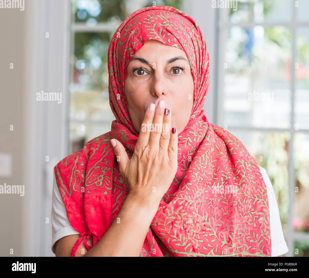 Im mittleren Alter muslimische Frau mit Kopftuch bedecken den Mund mit der Hand mit Schande für den Fehler, den Ausdruck von Angst erschüttert, die in der Stille Angst, geheime Konzept Stockfoto