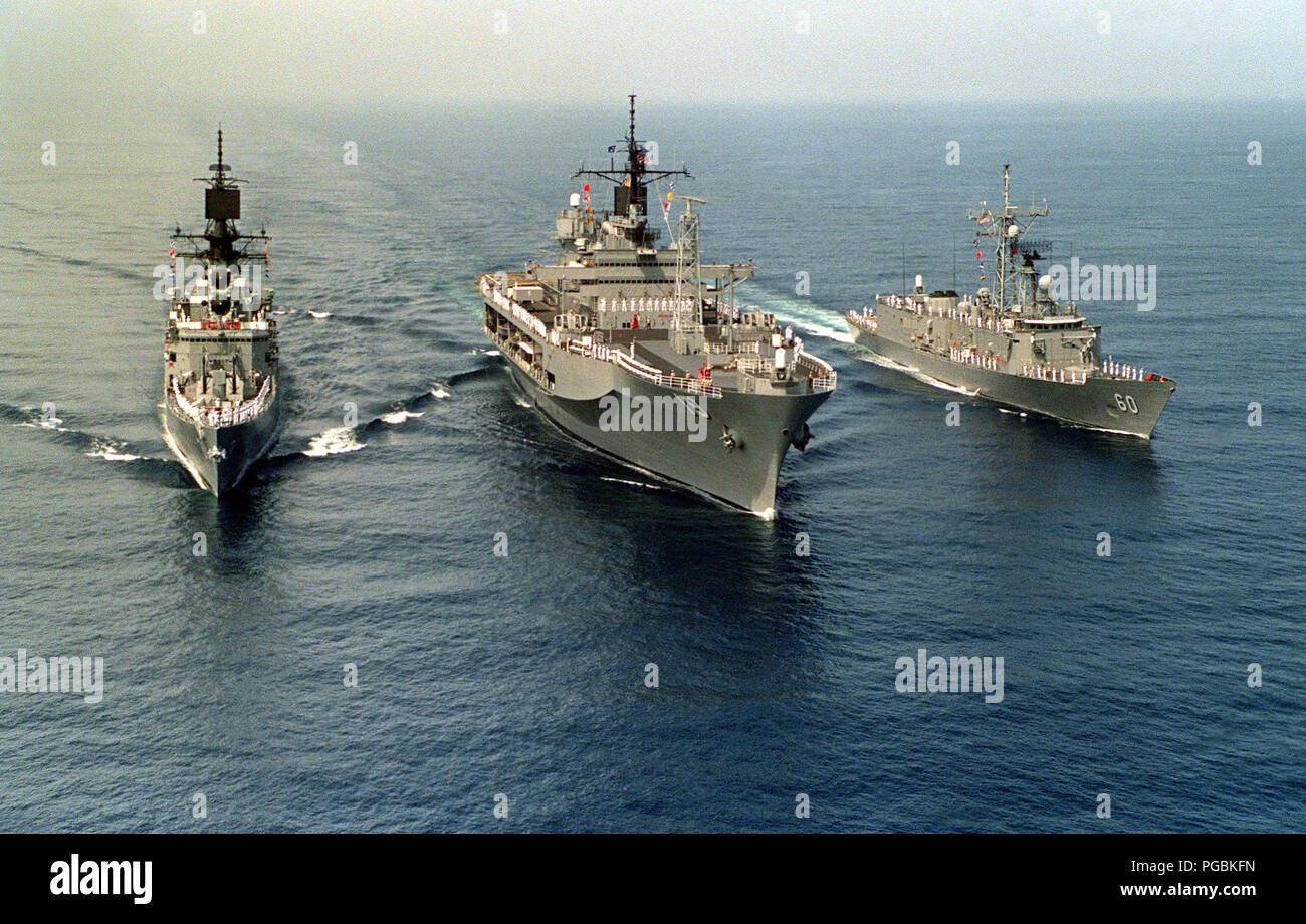 Offiziere und Matrosen Mann die Schienen der amphibischen Kommando Schiff USS BLUE RIDGE (LCC-19), dem Flaggschiff der Siebten Flotte, flankiert vom Lenkwaffen-kreuzer USS STERETT (CG-31), links, und der lenkwaffenfregatte USS RODNEY M. DAVIS (FFG-60) Stockfoto