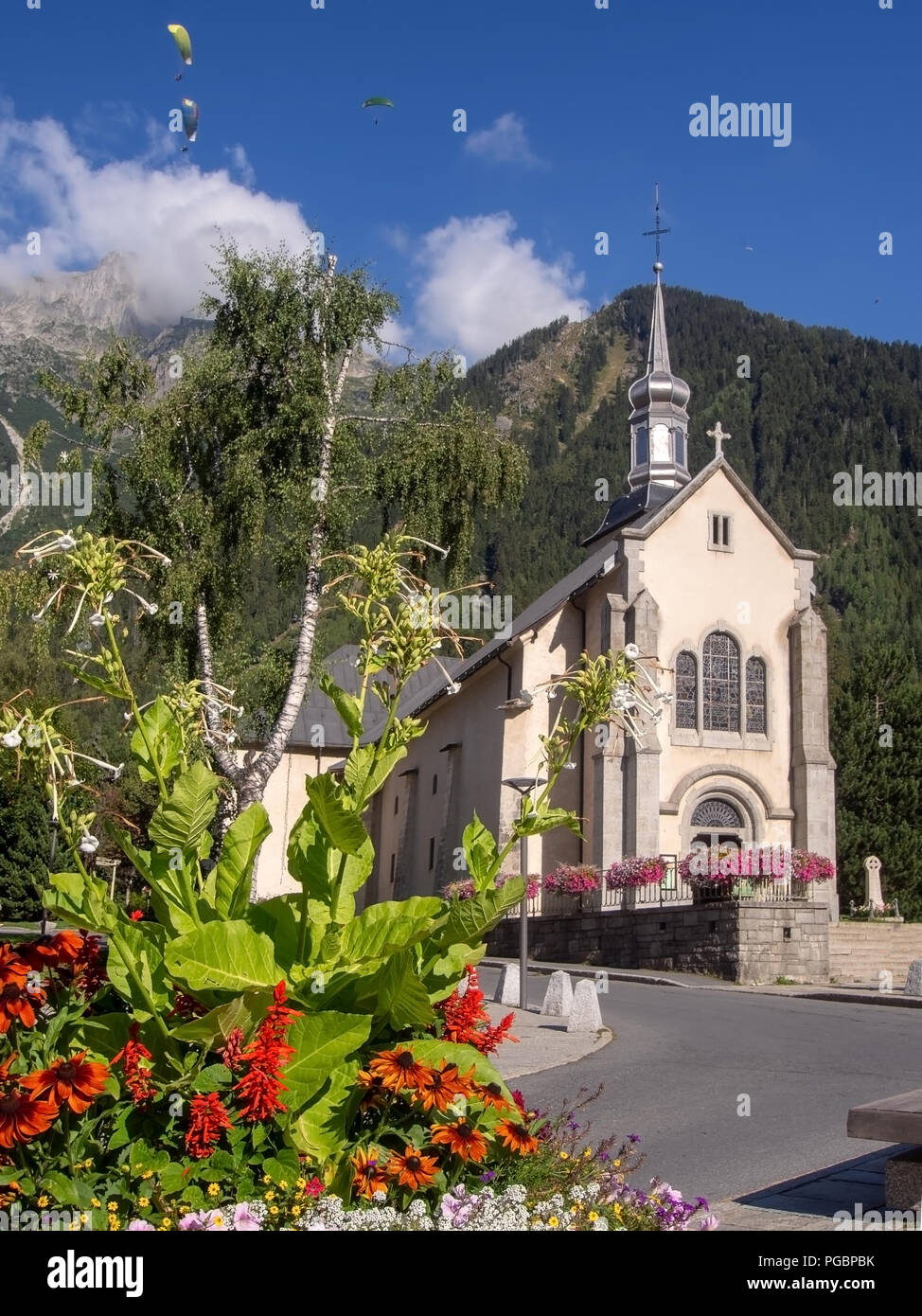 Chamonix Mont Blanc, Region Haute Savoie, Frankreich. Blick auf den Platz mit der katholischen Kirche von St. Michel im August mit Blumen und Gleitschirmen. Der Abschlepp-trennvorrichtung Stockfoto