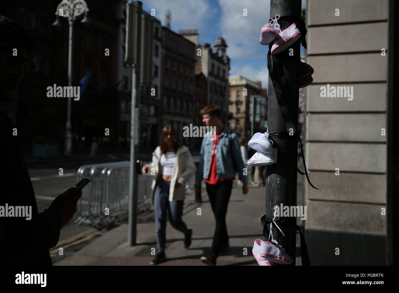 Demonstranten Riegel Baby Schuhe auf einen Posten, was bedeutet, dass die Kinder, die in der Mutter und Kind Wohnungen in Irland starben, während eines Protestes in Dublin vor Beginn des Besuchs in Irland von Papst Franziskus. Stockfoto