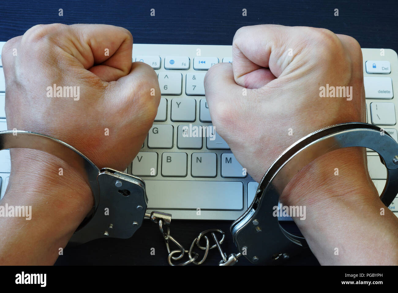 Die Hände in den Handschellen, über die Tastatur. Zensur im Internet oder Hacken. Stockfoto