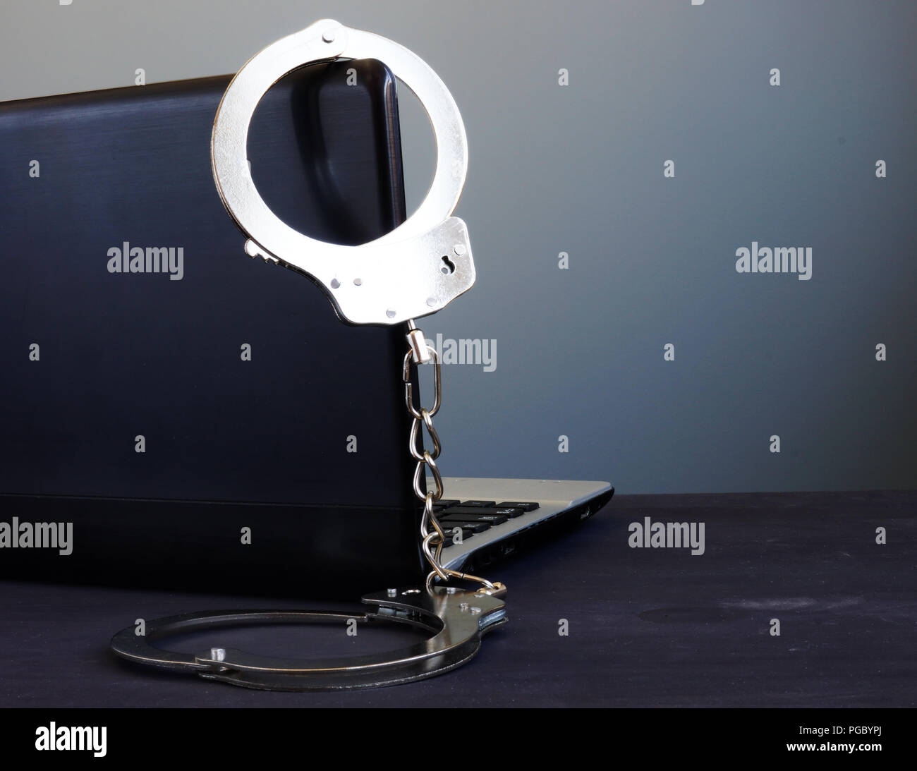 Handschellen auf einem Laptop. Internetkriminalität oder Hacken. Stockfoto