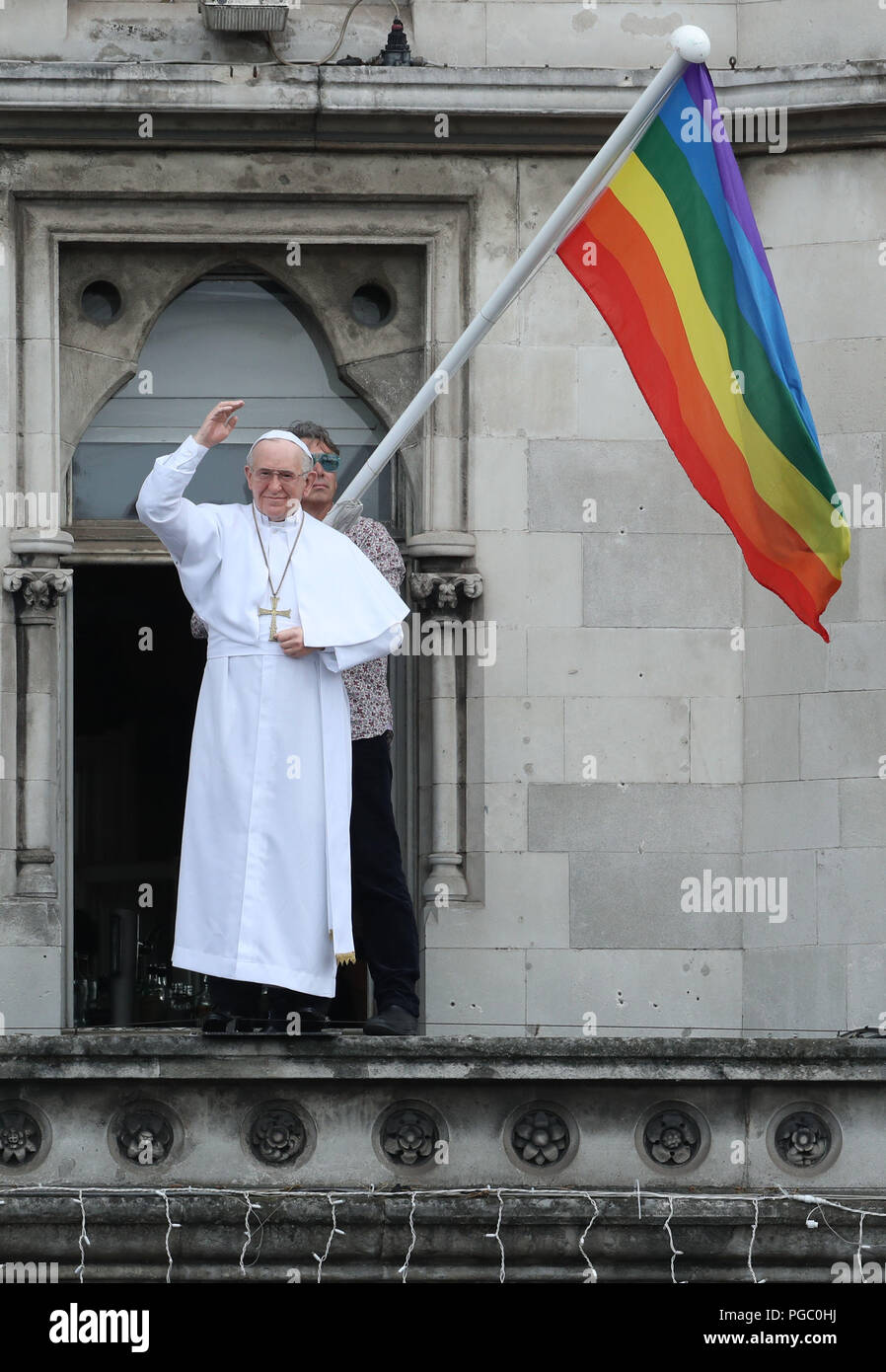 Ein Regenbogen Flagge ist neben einem Abbild von Papst Franziskus