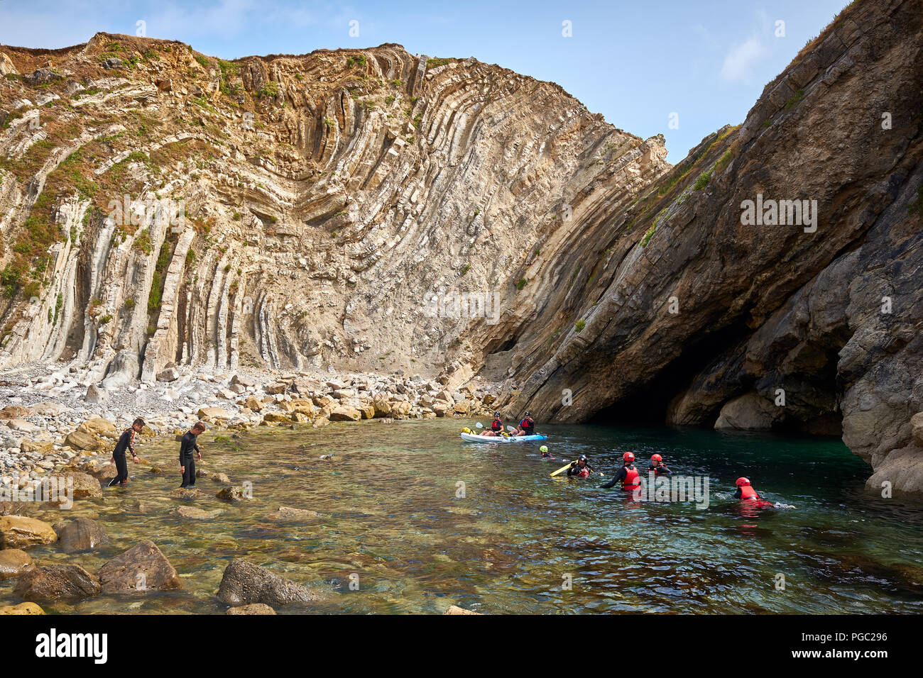 Lulworth/Dorset - 22. August 2018: Im Schatten einer geologischen Falte an der Küste von Dorset an der Treppe loch Menschen Paddel und nehmen Teil an coasteering Stockfoto