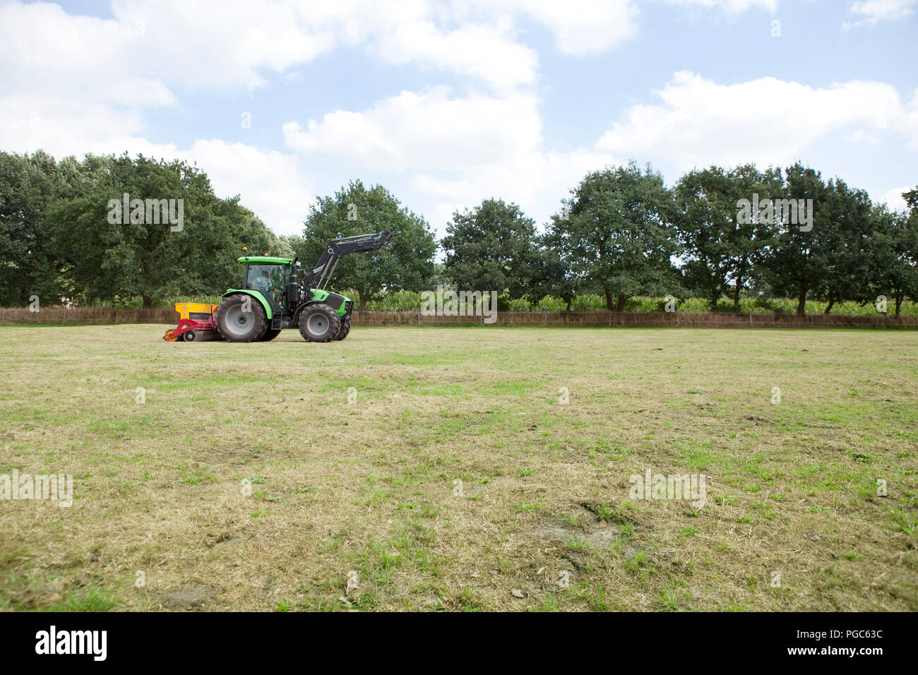 Eine moderne Traktor funktioniert der Rasen auf einem Pferd auf der Weide Stockfoto