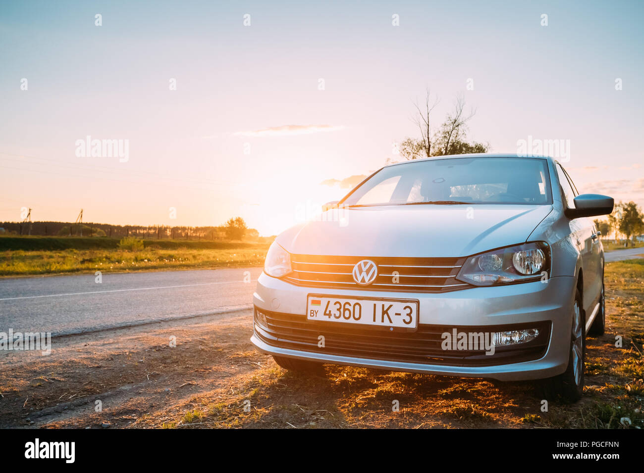 Gomel, Belarus - 16. Mai 2017: VW Volkswagen Polo Vento Limousine Parkplatz in der Nähe asphaltierte Landstraße im sonnigen Sonnenuntergang. Sonnenlicht über Straße in Sunrise. Stockfoto