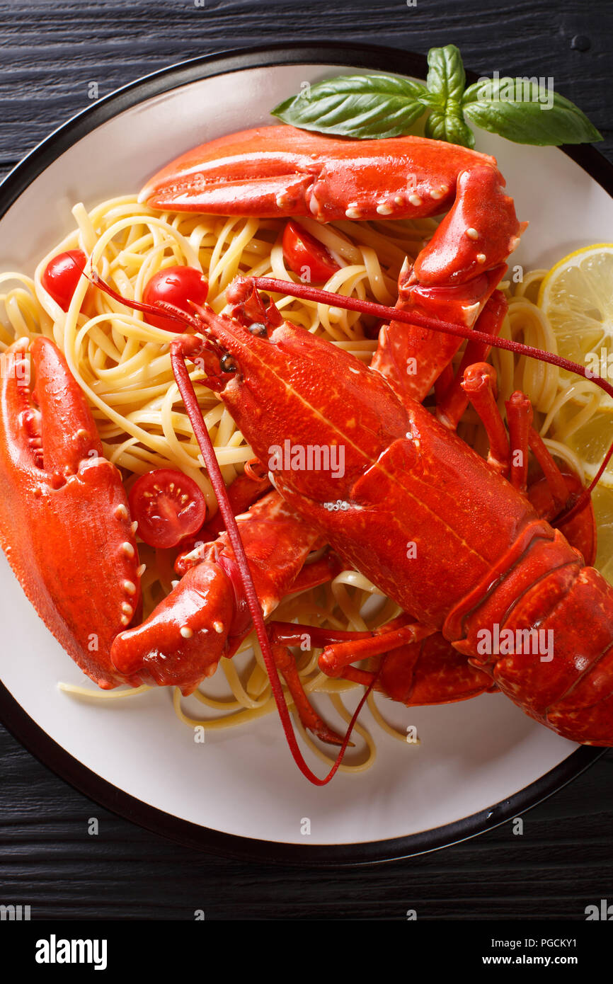 Luxus essen Rezept: Spaghetti und gekochten Hummer, Tomaten, Zitrone und frischen Kräutern close-up auf einem Schild auf einem schwarzen Hintergrund. Vertikal oben Ansicht von ab Stockfoto