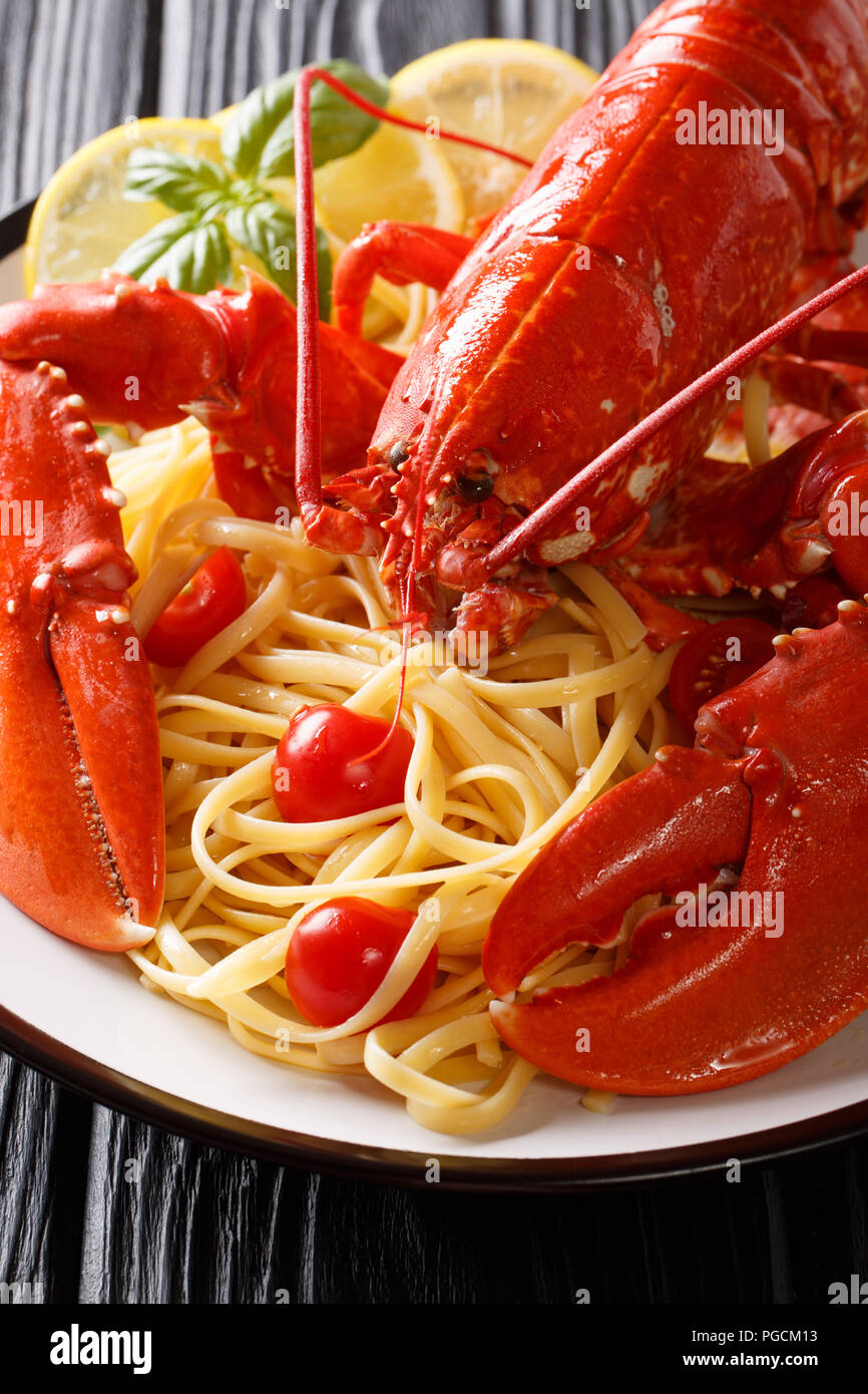 Italienisches Rezept Spaghetti mit gekochten Hummer, Tomaten, Zitrone und frischen Kräutern close-up auf einem Teller. Vertikale Stockfoto