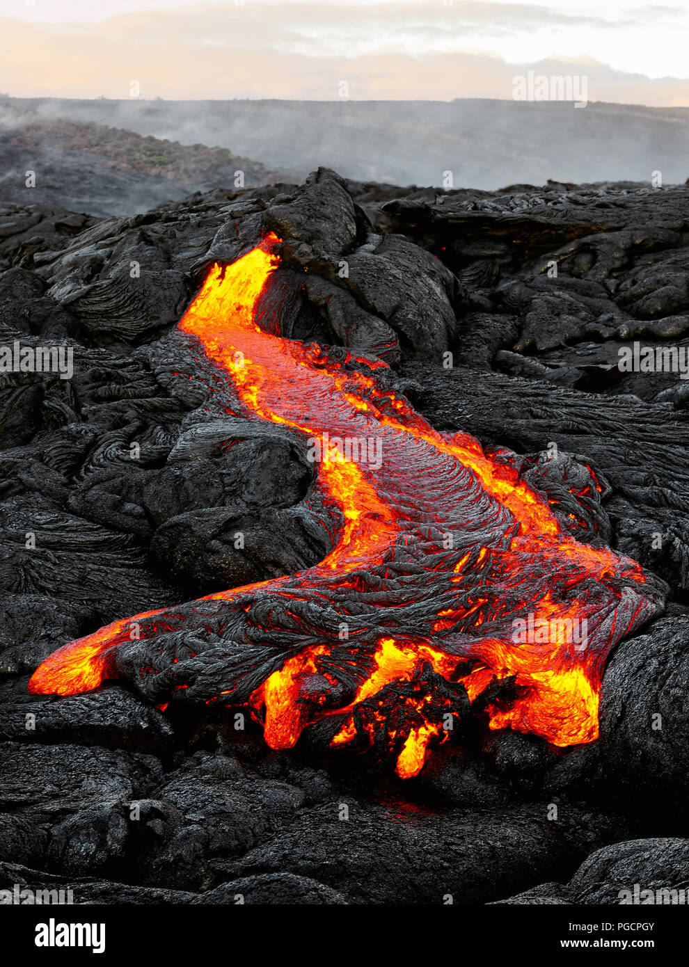 Ein Lavastrom Austritt aus einer Masse Spalte und fließt in einem schwarzen vulkanischen Landschaft, in den Himmel zeigt das erste Tageslicht - Ort: Hawaii, Big Island, Stockfoto