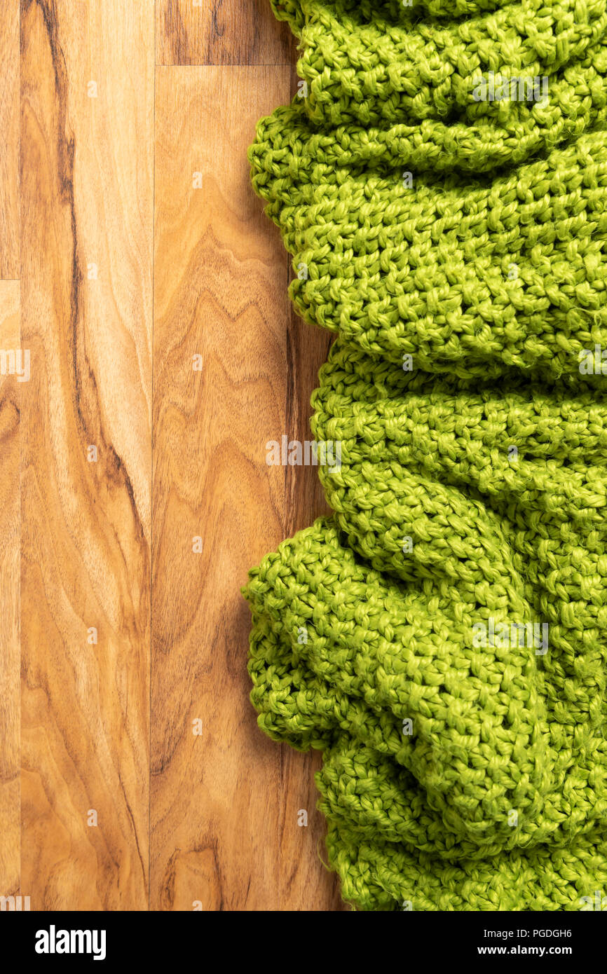 Wolldecke, grün, aus Gewirken große chunky Garn. Nahaufnahme der gestrickte Decke auf Holz- Hintergrund. Stockfoto