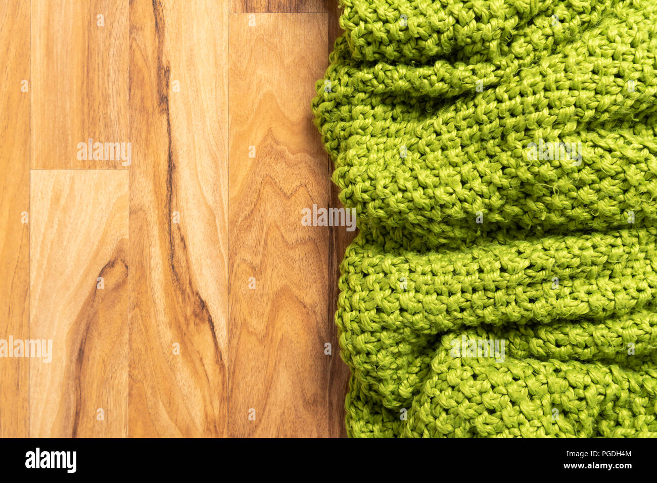 Wolldecke, grün, aus Gewirken große chunky Garn. Nahaufnahme der gestrickte Decke auf Holz- Hintergrund. Stockfoto